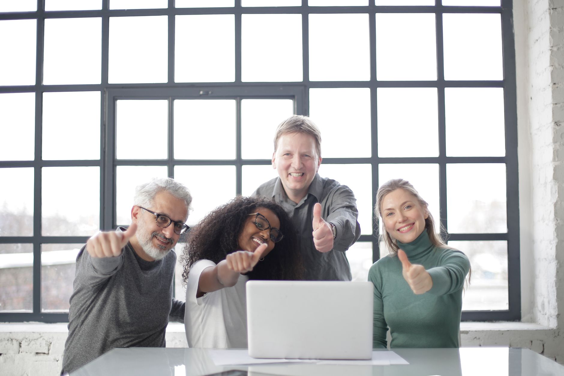 happy team with laptop showing thumb up gesture